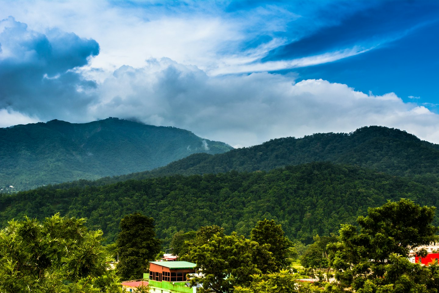 Colorful buildings nestled among rolling green forested mountains.