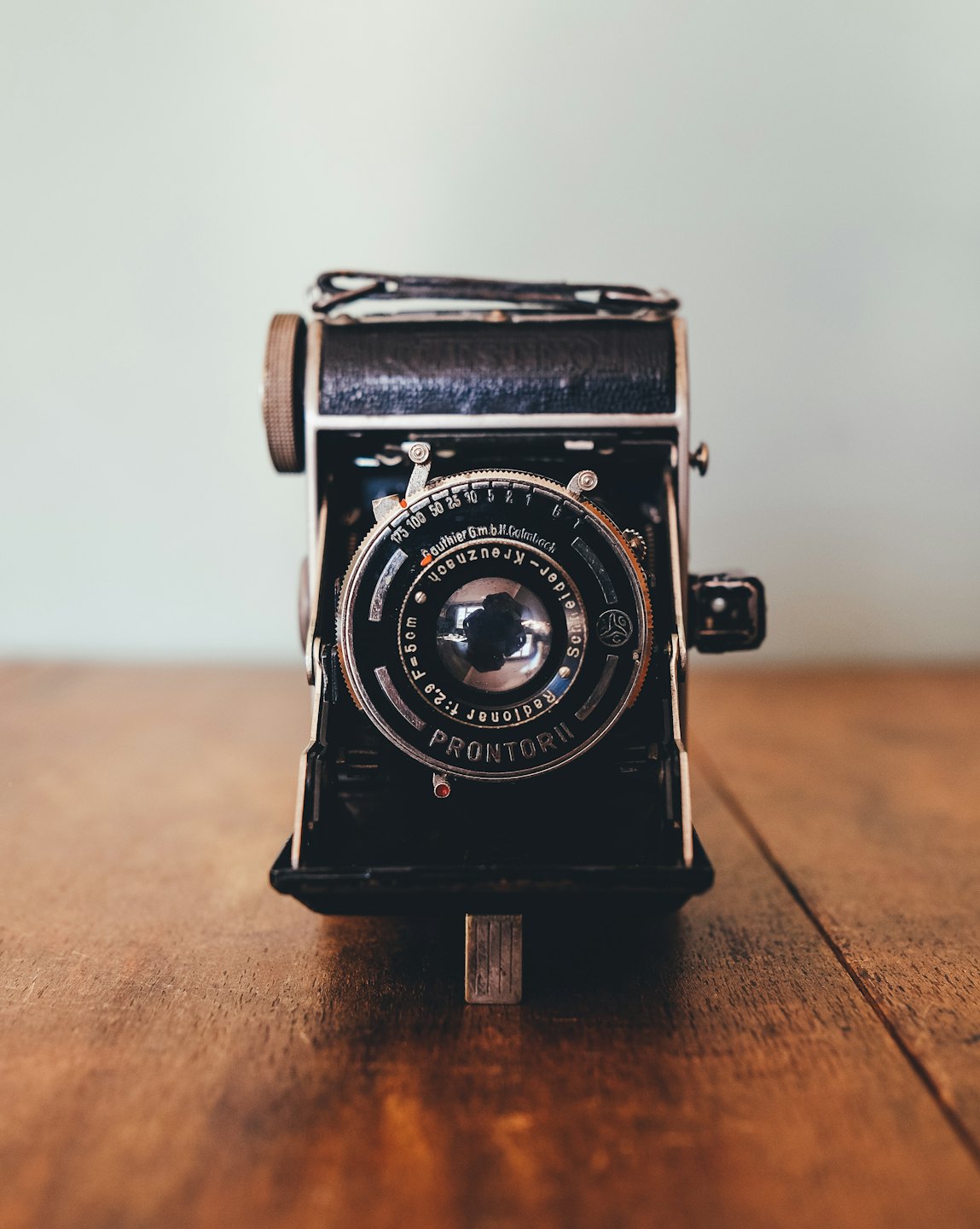 Vintage black folding camera on a wooden table.